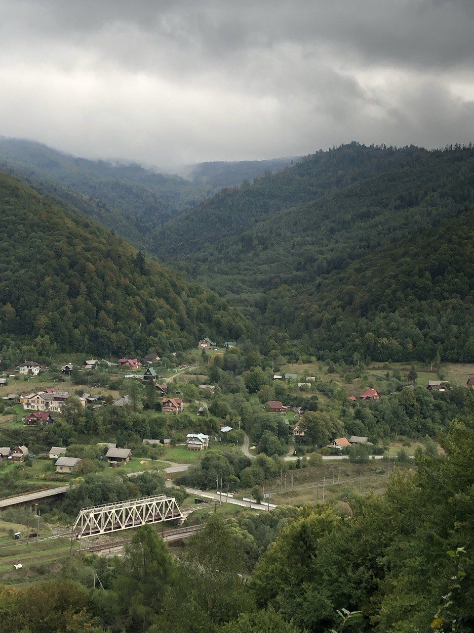 Долина Опору згори: село, залізничний міст, гори під хмарами